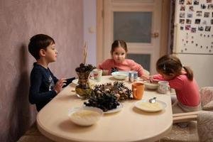 Three kids have dinner together in the kitchen. photo