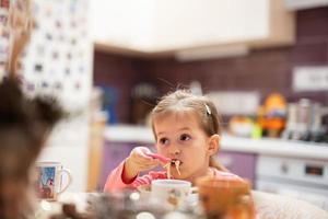 Girl has dinner in kitchen, eat bouillon. photo