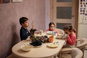 Three kids have dinner together in the kitchen. photo