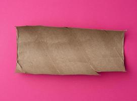 torn piece of brown paper on pink background photo