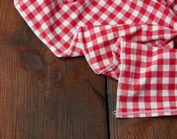 toalla de cocina textil roja y blanca sobre un fondo de madera marrón de tablas viejas foto