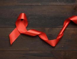 red silk ribbon folded into a loop on a brown wooden background photo
