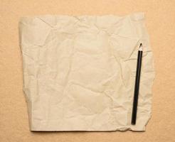 empty torn sheet of brown craft paper and black wooden pencil photo