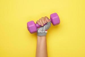 female hand in a pink sports glove holds a purple one kilogram dumbbell photo