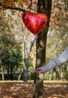 mano femenina sosteniendo un globo rojo en forma de corazón foto