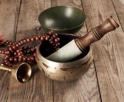 Tibetan singing copper bowl with a wooden clapper on a brown wooden table, objects for meditation and alternative medicine photo