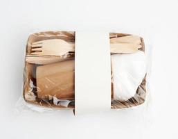 platos y tazas de papel de papel artesanal marrón y tenedores y cuchillos de madera aislados en un fondo blanco foto