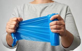 woman holding a roll of blue garbage bags in her hand photo