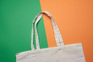 empty white textile reusable cotton shopping bag on a green background photo