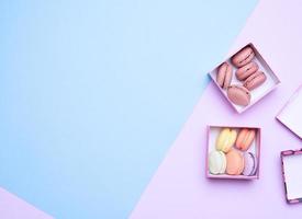 baked round multicolored macarons in square boxes on a colored pastel background photo