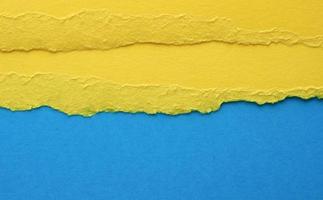 background with torn edges of yellow paper, blue backdrop, close up photo