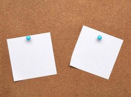 blank square white sheet of paper attached with blue button on a brown background photo