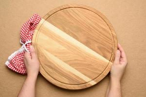 woman holding empty round wooden pizza board in hand photo