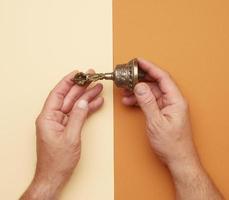 male hands hold a copper Tibetan ritual bell photo