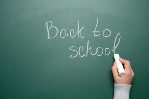 lettering back to school in white chalk on a green chalk board photo