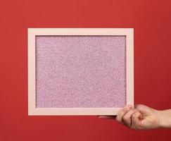 woman holds an empty pink frame on a red background photo