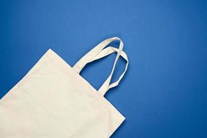 empty beige textile bag on blue background, rejection of plastic bags photo