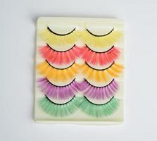 pestañas postizas multicolores en envases de plástico sobre un fondo blanco foto