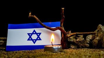 bandera israelí y velas encendidas frente a ella, día de la memoria del holocausto foto