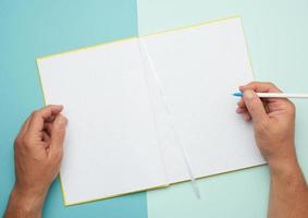 two male hands holding open notepad with empty white sheets photo