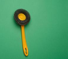 yellow plastic brush for cleaning the house on a green background photo