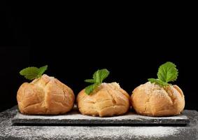 baked custard eclairs and sprinkled with powdered sugar and decorated with a mint leaf photo