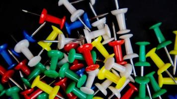 multicolored thumbtacks on a black background photo