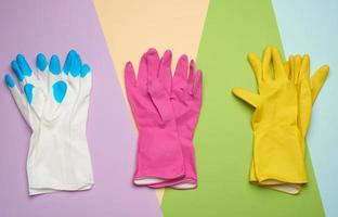 three pairs of protective rubber gloves on a colored background photo