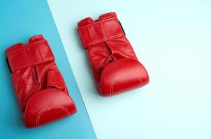 un par de guantes de boxeo de cuero rojo sobre un fondo azul foto