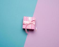 cardboard box and pink ribbon with bow on blue lilac background photo