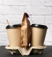 two brown paper disposable cups with a plastic lid stand in the tray photo