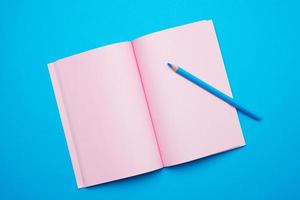 open notepad with empty pink sheets on a blue background photo