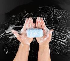 proceso de lavarse las manos con jabón azul, partes del cuerpo en espuma blanca sobre fondo negro foto