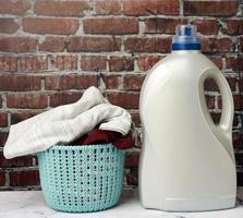 plastic round laundry basket and gray bottle with liquid laundry powder photo
