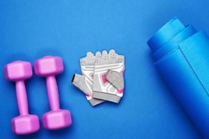 pair of dumbbells, sports gloves and blue sports mat, top view photo