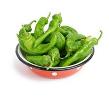 green hot pepper pods in red metal plate isolated on white background photo