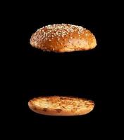 baked sesame seed round bun cut in half, halves fried and levitating in air over each other photo