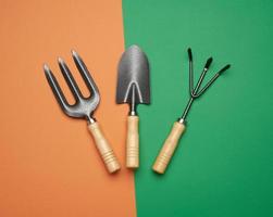 garden set of shovels, rakes, pitchforks on a green-orange background photo