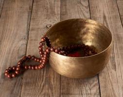 Tibetan singing copper bowl with a wooden clapper on a brown wooden table photo