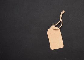 empty paper brown rectangular price tag on a rope on a black background photo