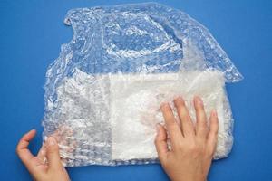 two female hands are wrapping the item in a transparent plastic wrap with bubbles photo