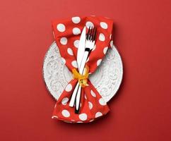 white round ceramic plates, fork with knife on a red background, top view. Table setting, copy space photo