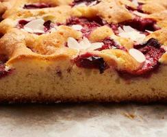 baked slices of sponge cake with plums on brown paper photo