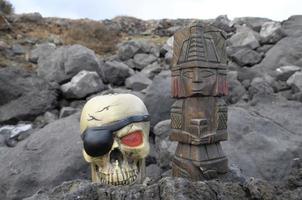 Pre-Columbian miniature and pirate skull on the ground photo