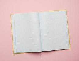 libreta abierta con hojas blancas vacías sobre un fondo rosa foto