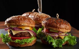 delicious burgers with fried beef cutlet, tomato, lettuce and onions, crispy white wheat flour bun with sesame seeds photo