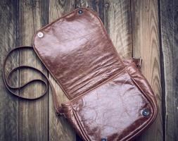 open leather brown bag with long strap on wooden background photo