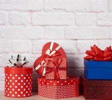 stack of various boxes with gifts on white brick background photo