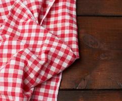 red-white textile kitchen towel on a brown wooden background from old boards photo