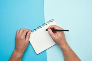 two male hands holding open notepad with empty white sheets photo